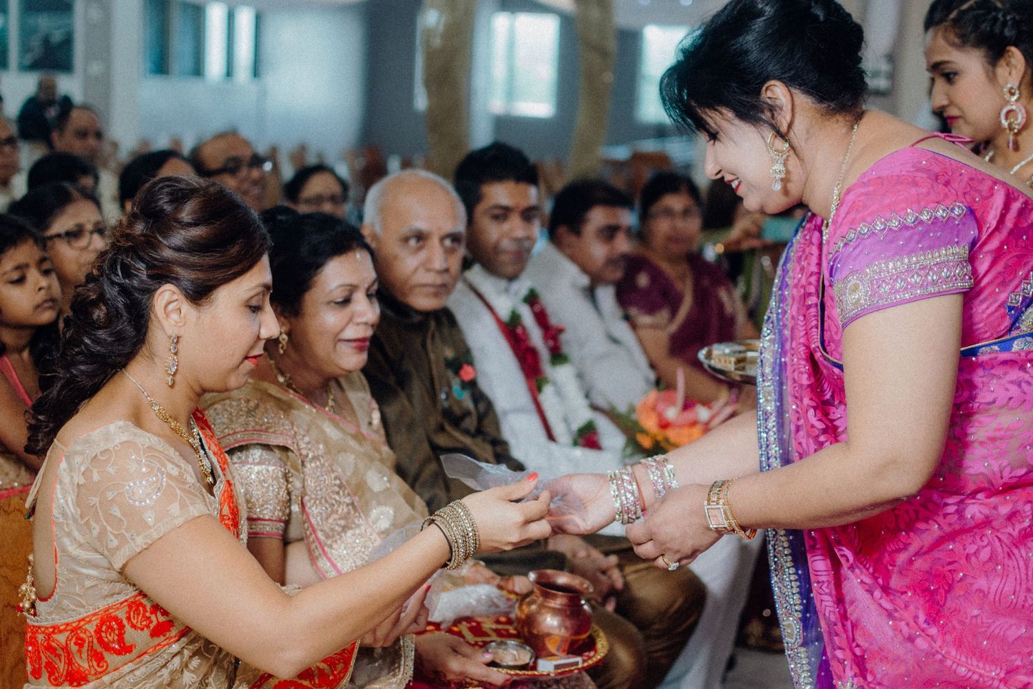 Traditional wedding ceremony ritual with guests in colorful saris exchanging items.