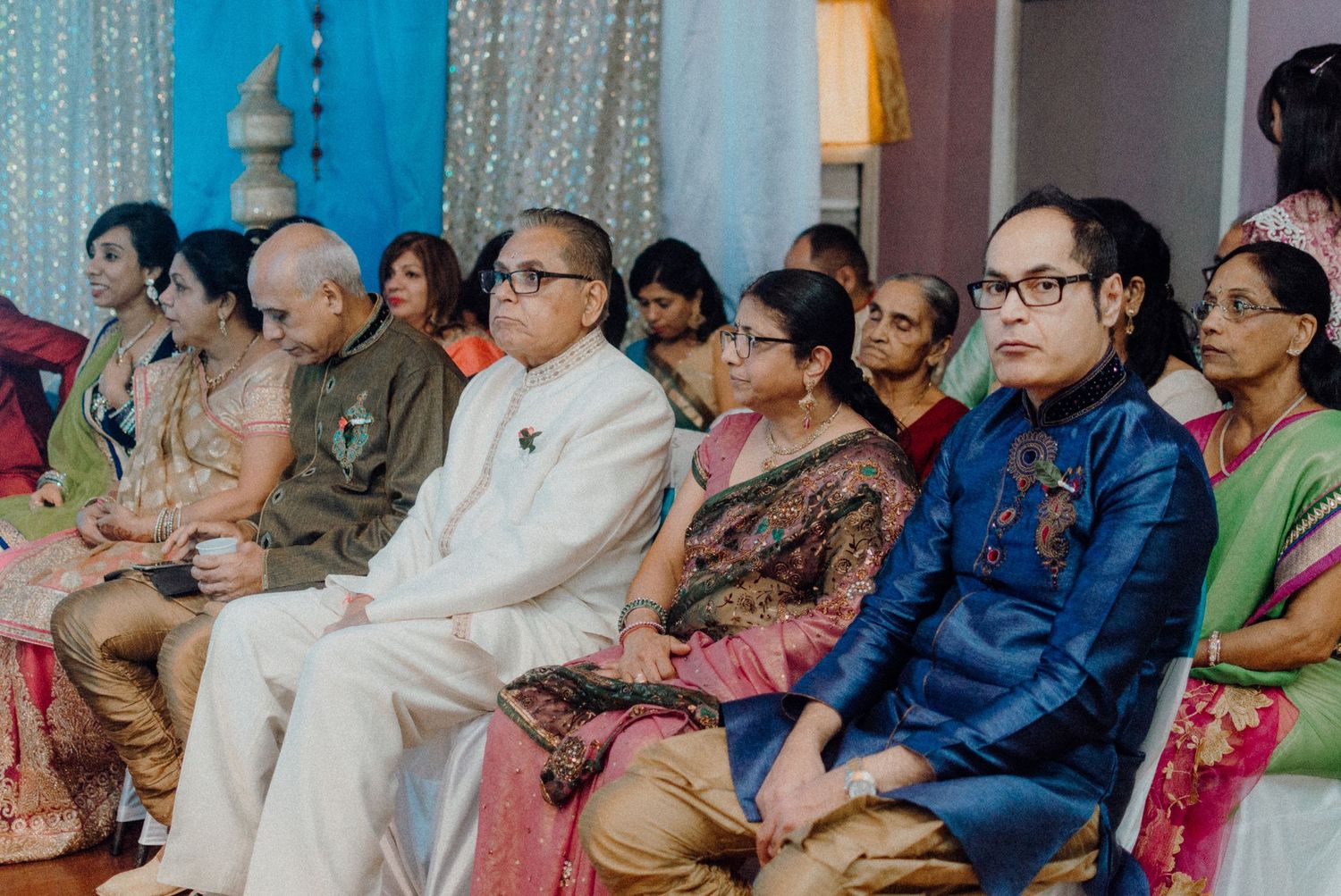 Audience members in traditional Indian attire seated in rows watching an event.
