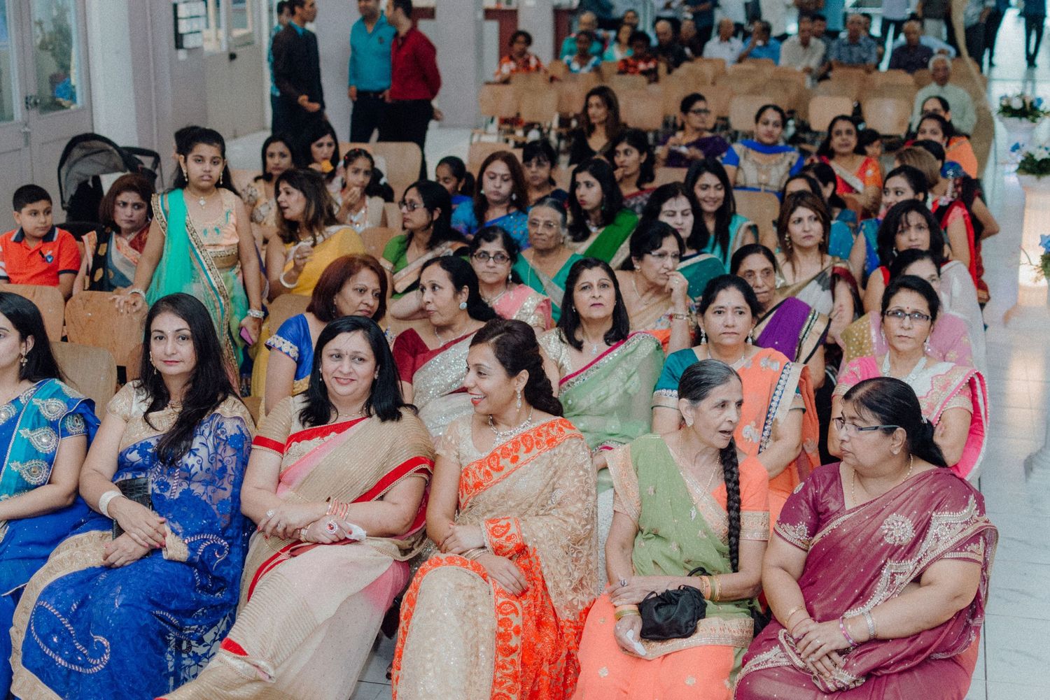 Guests in vibrant sarees seated in rows during an Indian celebration.