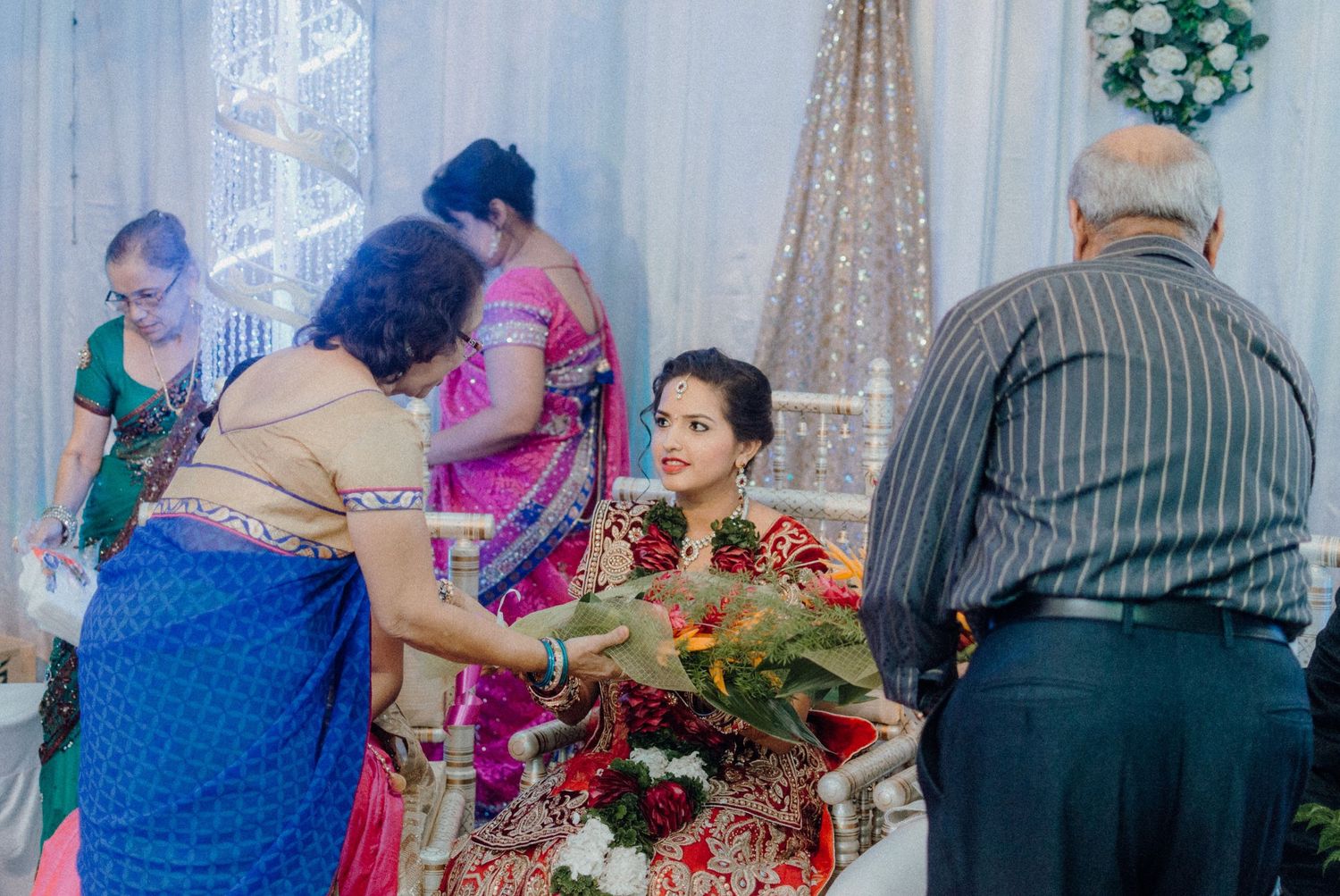 Family members giving blessings and gifts during an Indian wedding celebration.