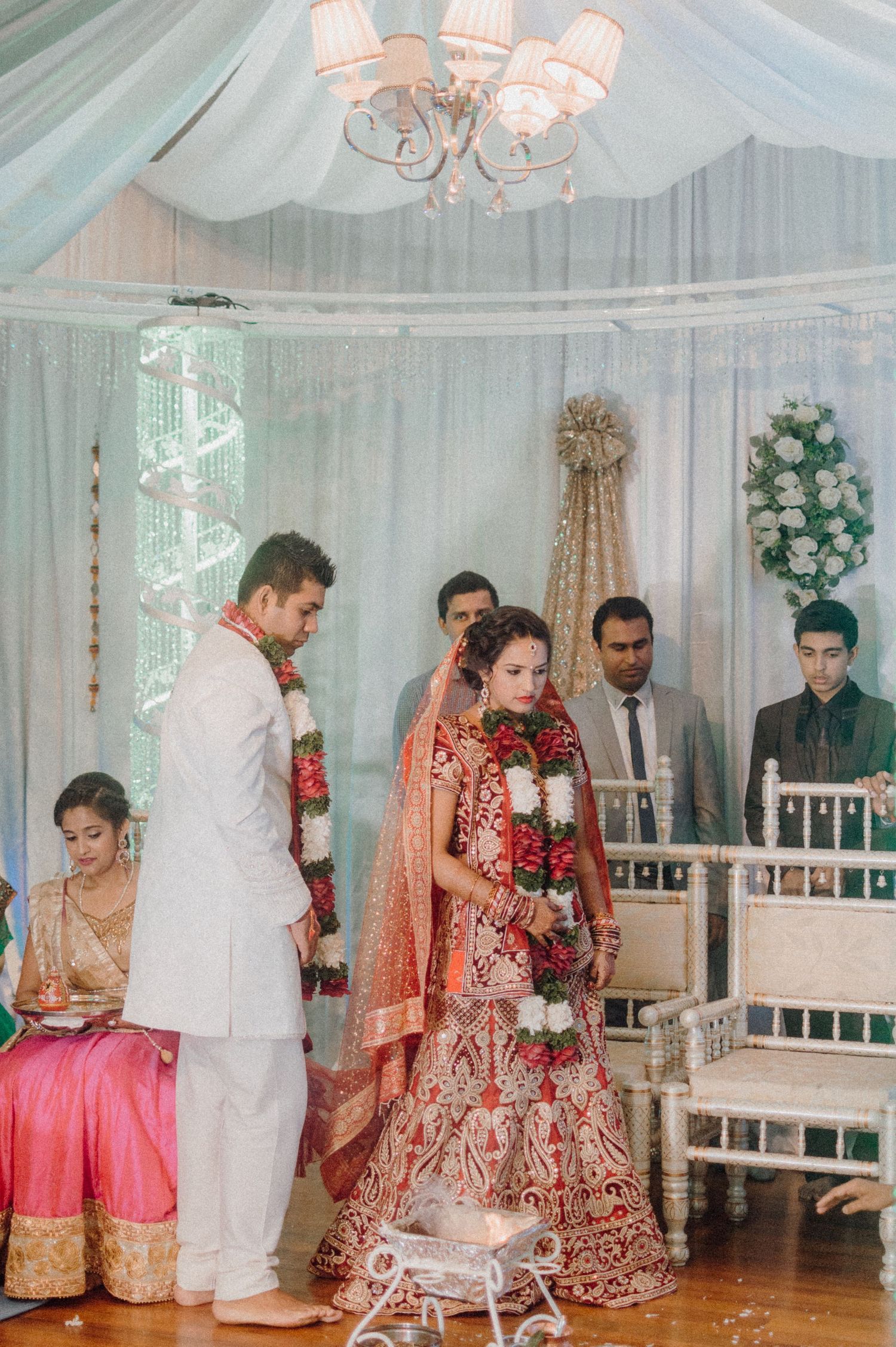 Elegant Indian wedding ceremony setup with chandelier and draped fabric decorations.