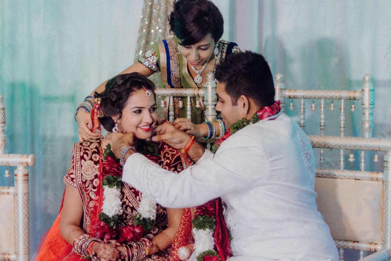 Traditional wedding ceremony where couple in red and white attire share a sweet moment during their marriage rituals.