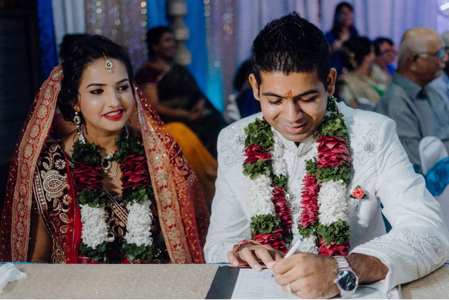 Traditional wedding ceremony with couple in formal attire signing documents.