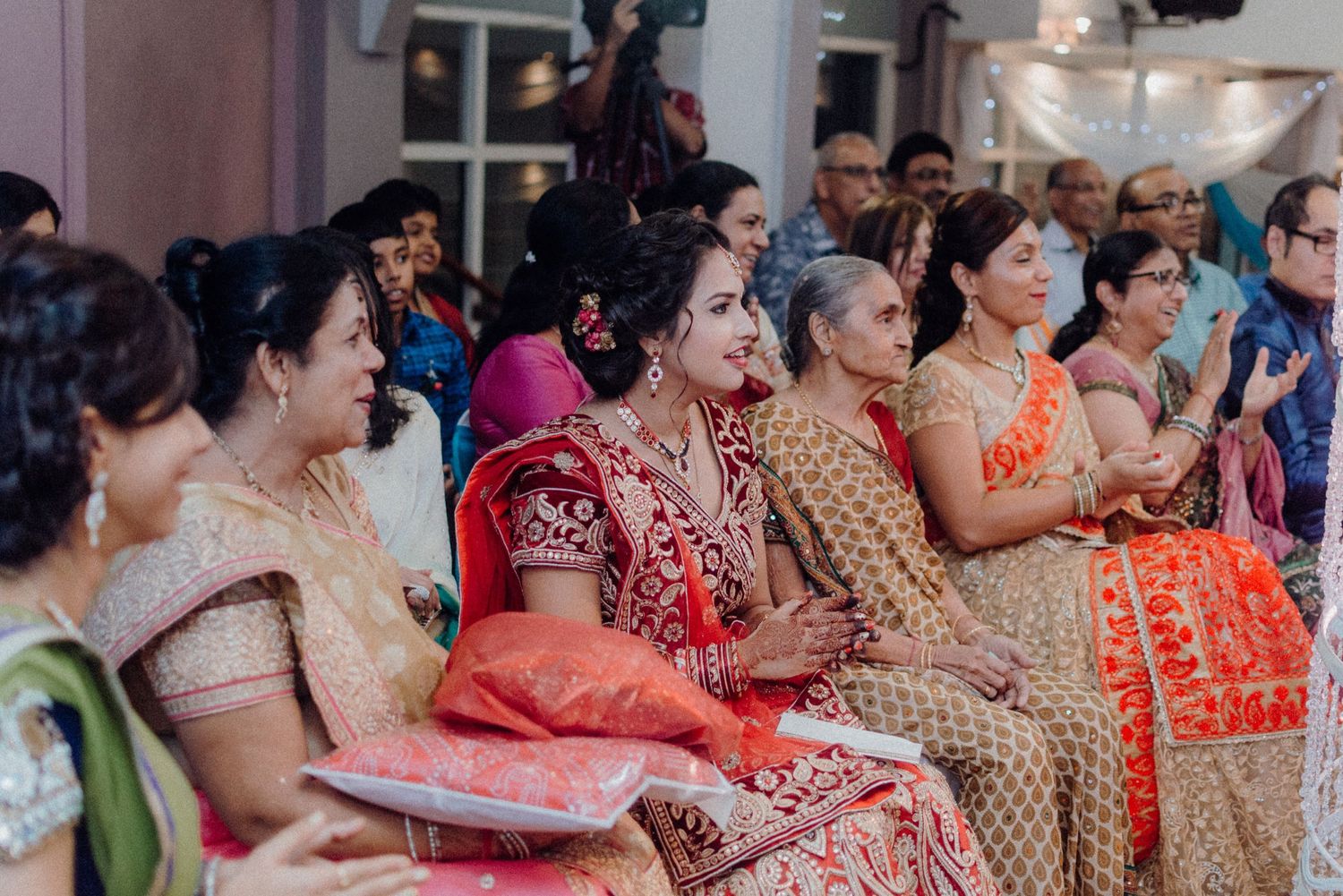 A group of guests in vibrant traditional Indian attire seated at a wedding ceremony.