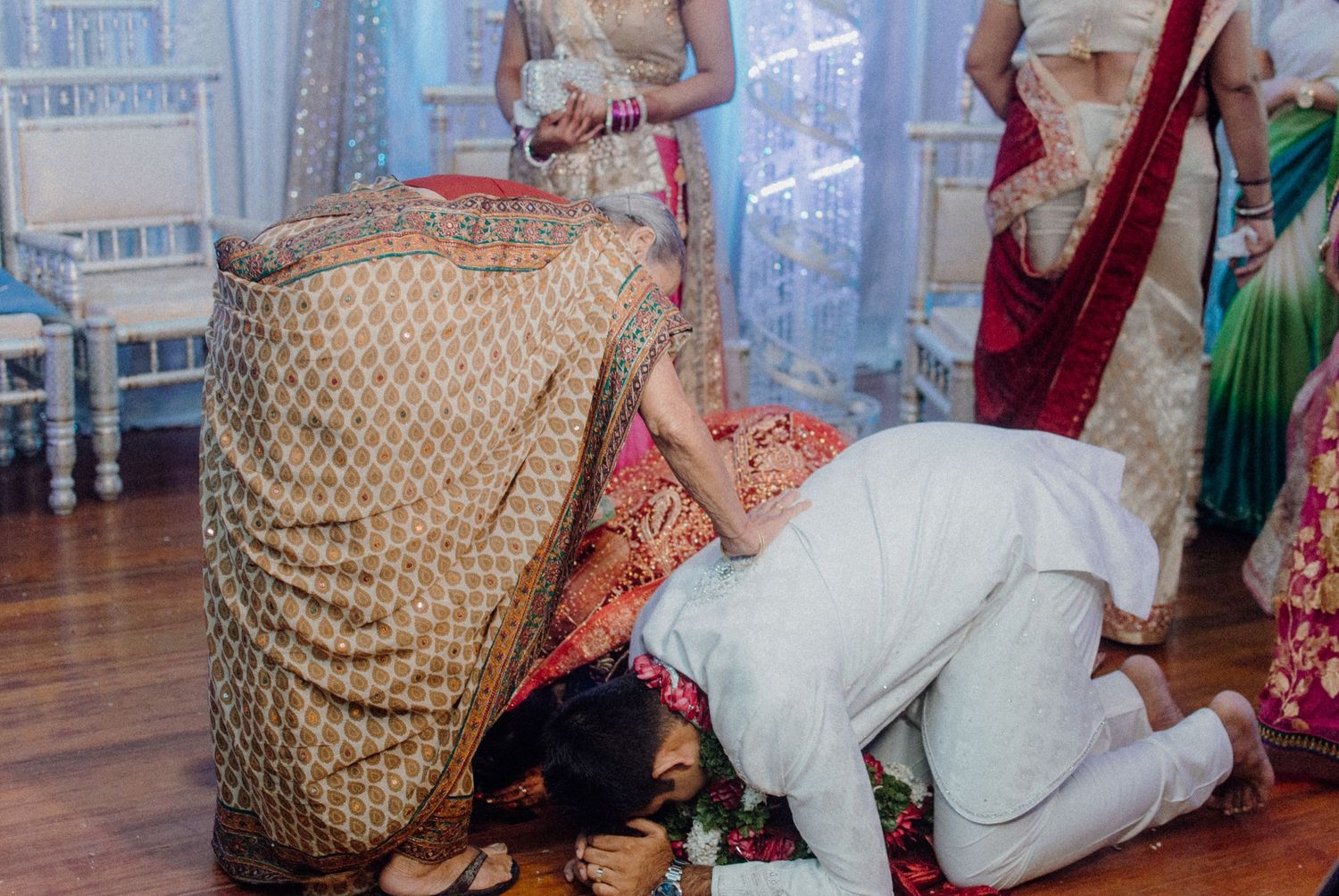 Traditional Indian wedding ritual with person bowing in respect wearing formal attire.
