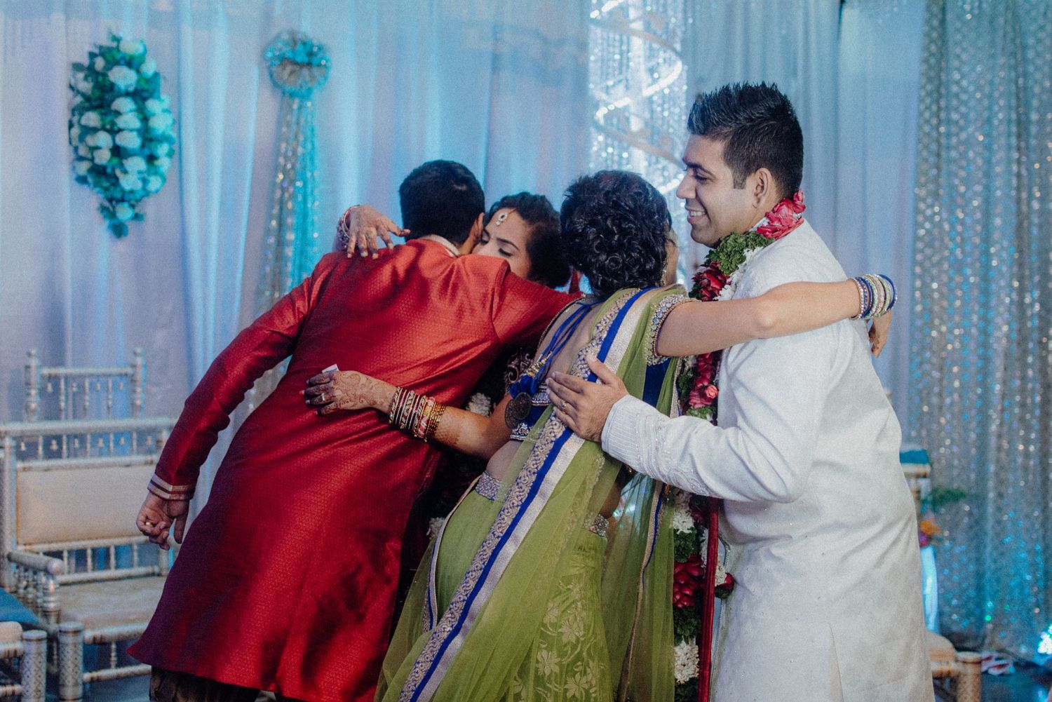 Family members sharing a group hug during an Indian wedding celebration.