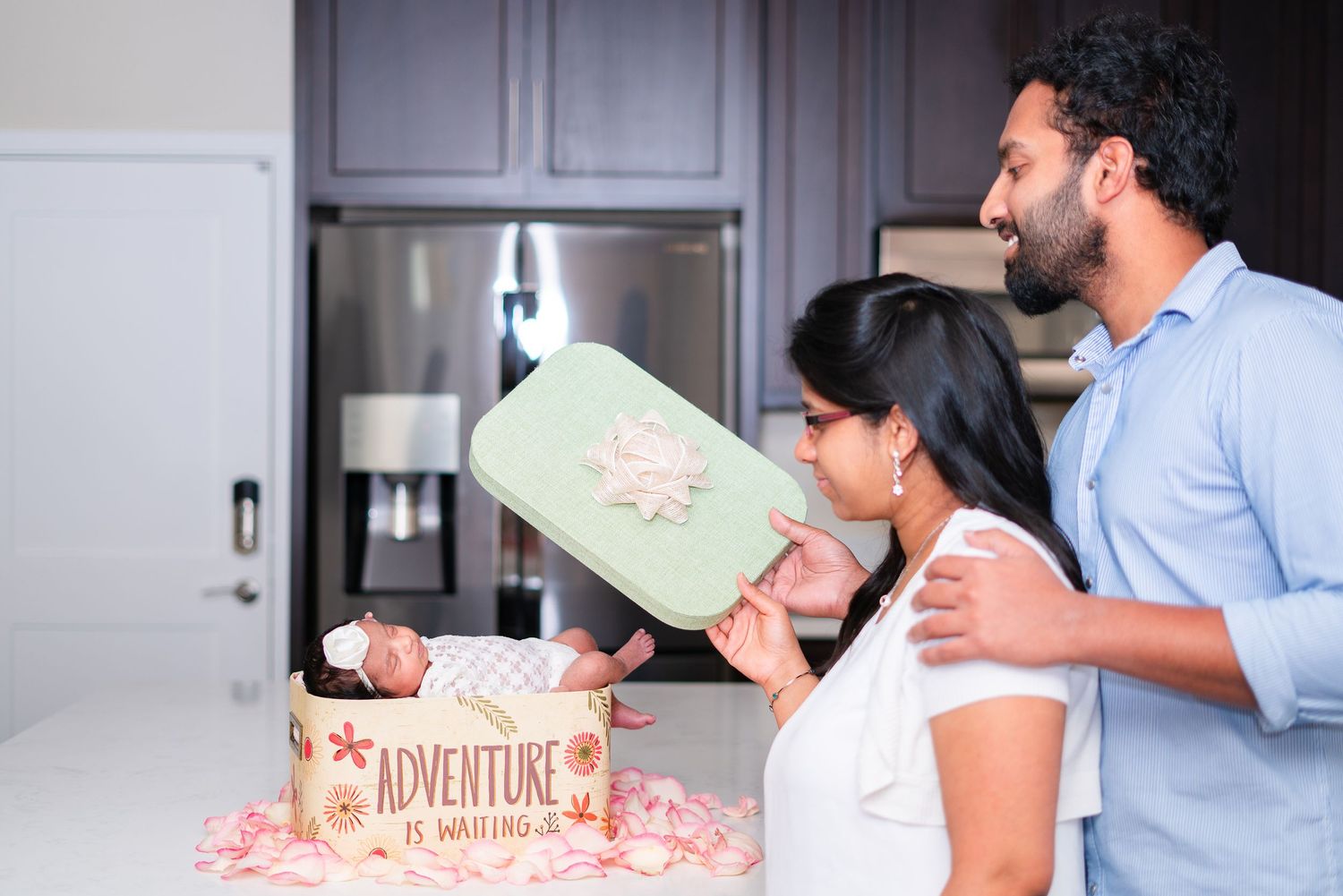 Parents revealing the baby nestled in a gift box, showing their newborn in a client in-home Lifestyle photo session in Livermore, CA