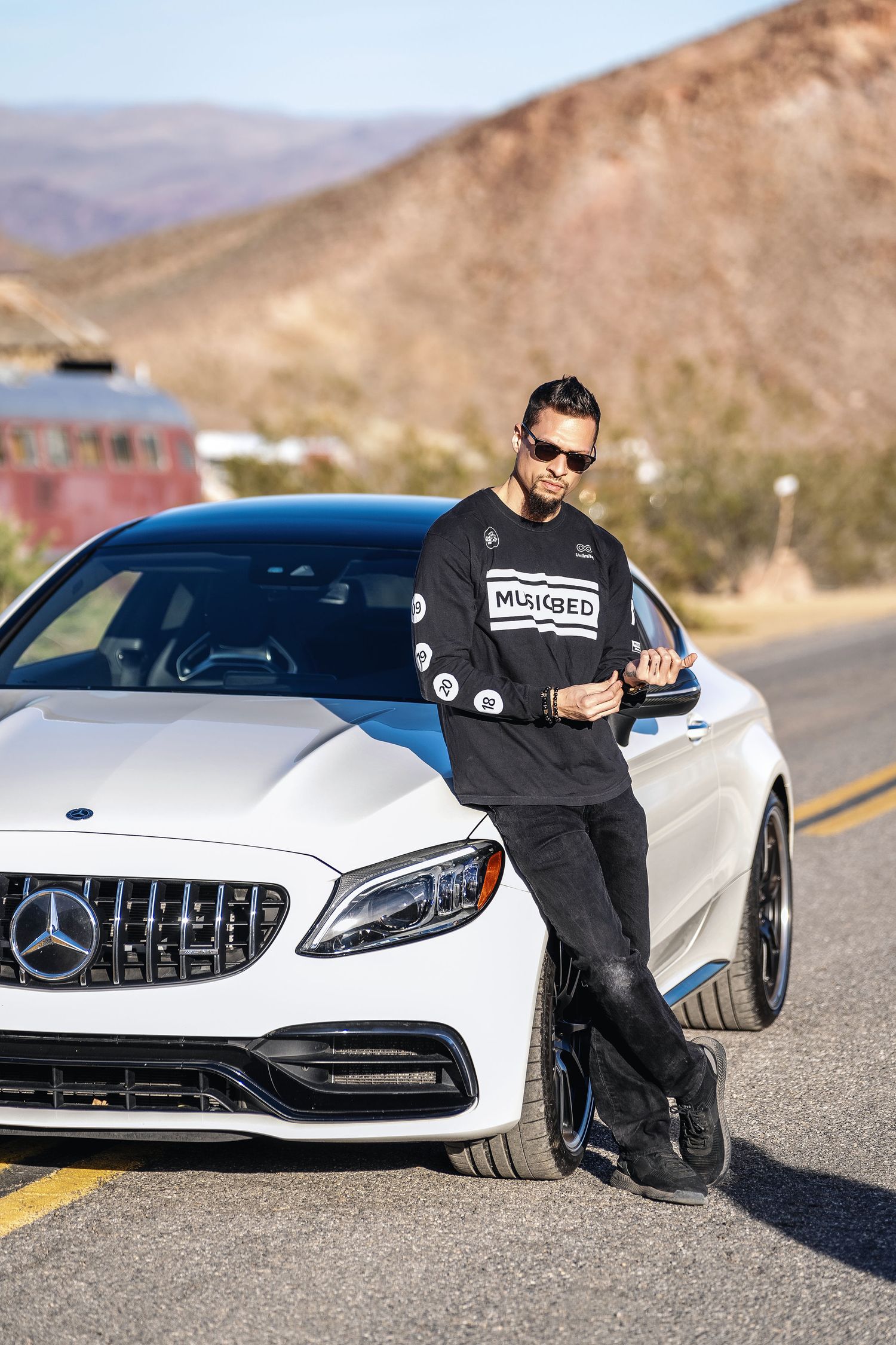 A destination wedding videographer Nate Templeton of Templeton Image leaning up against a Mercedes C63 Coupe during a photowalk