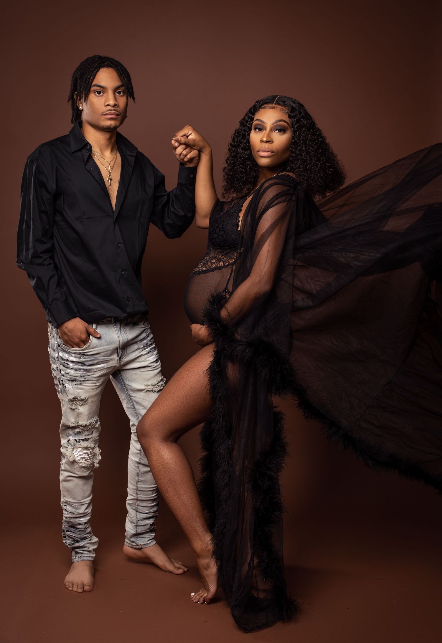 Stylish maternity portrait with flowing black robe and casual partner pose.