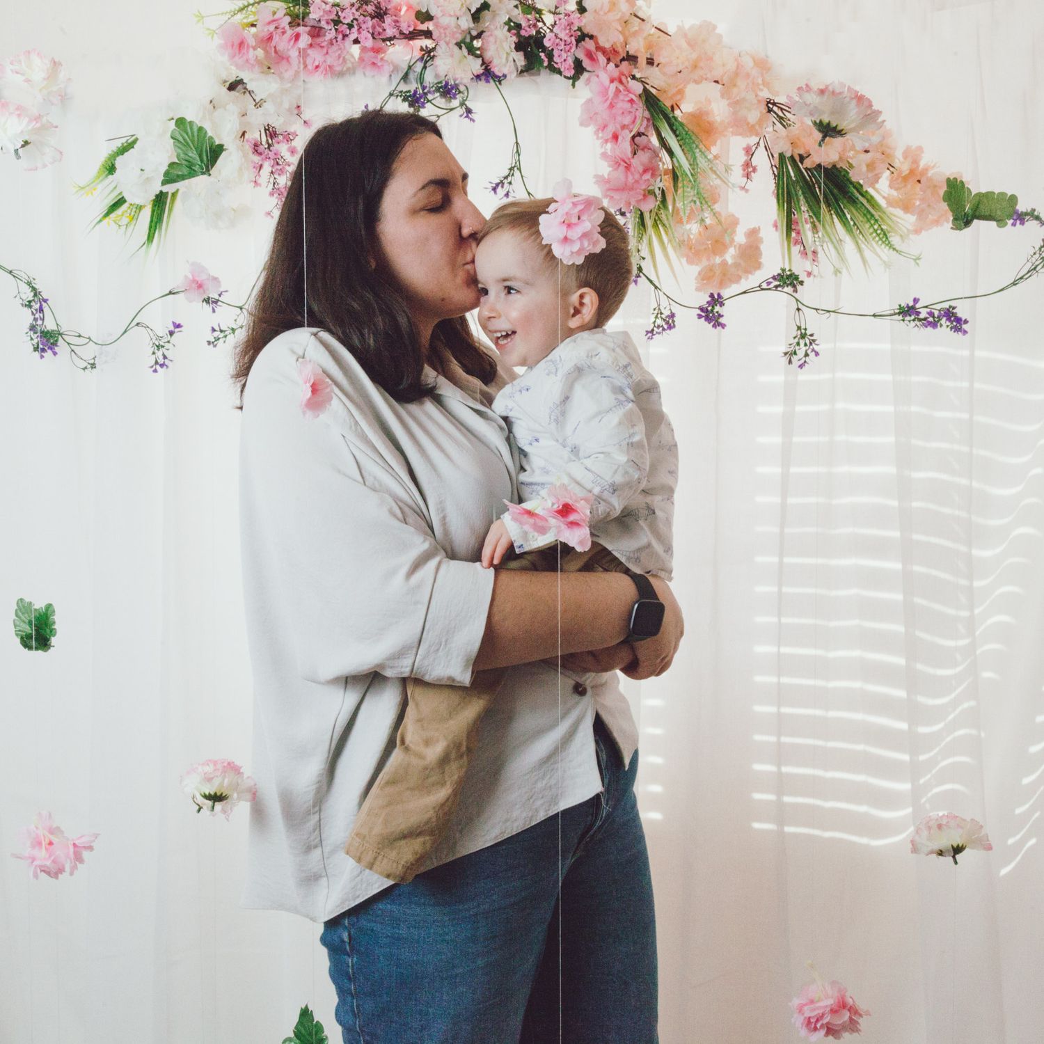 Mother kissing her son under the falling flowers, captured by Maria Photography, a family photographer in Gosport.