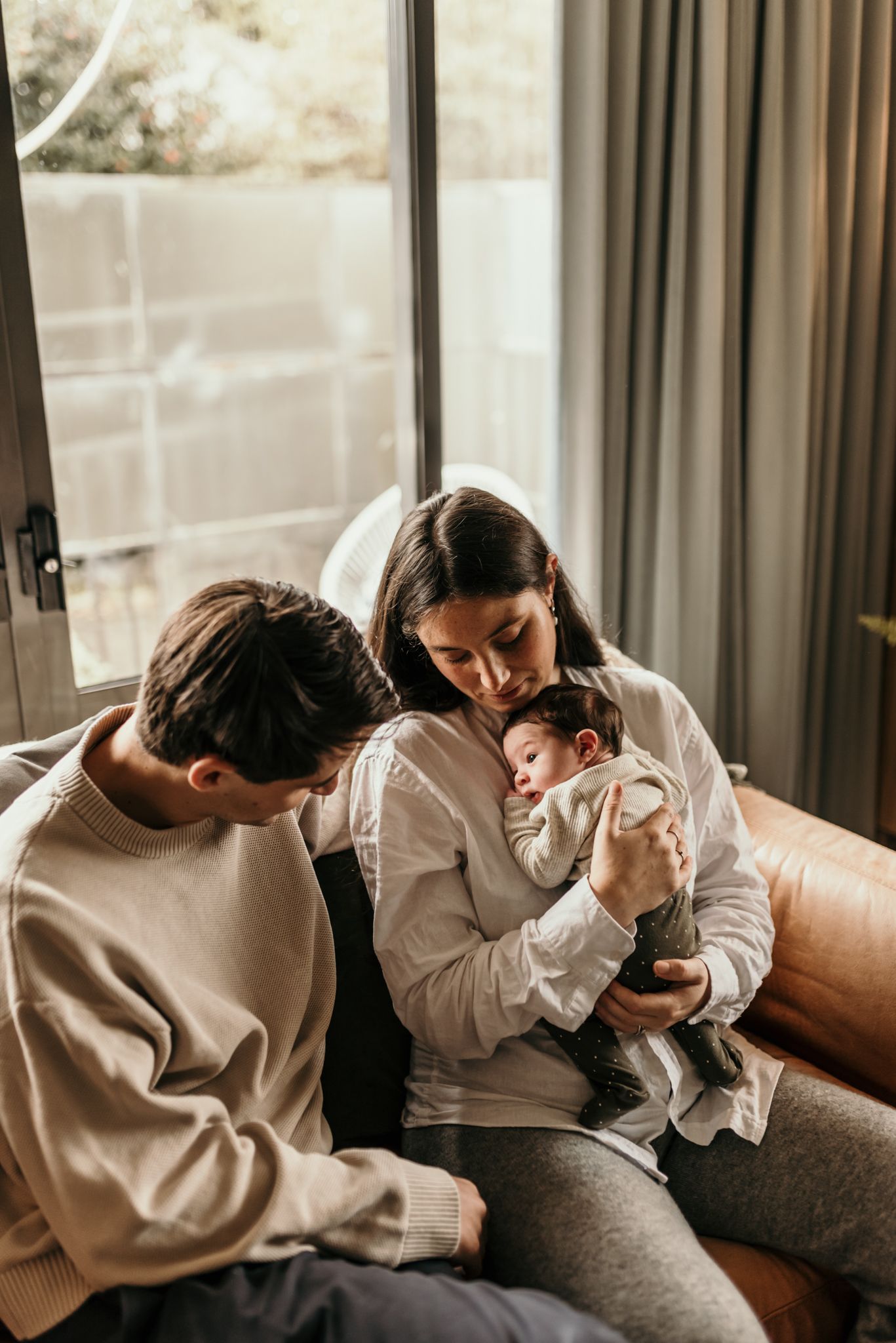 Intimate family moment with newborn baby in cozy living room setting.