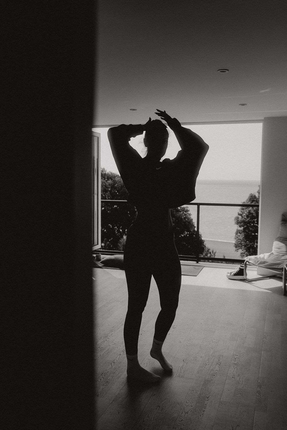 Silhouette figure stretching in front of bright window.