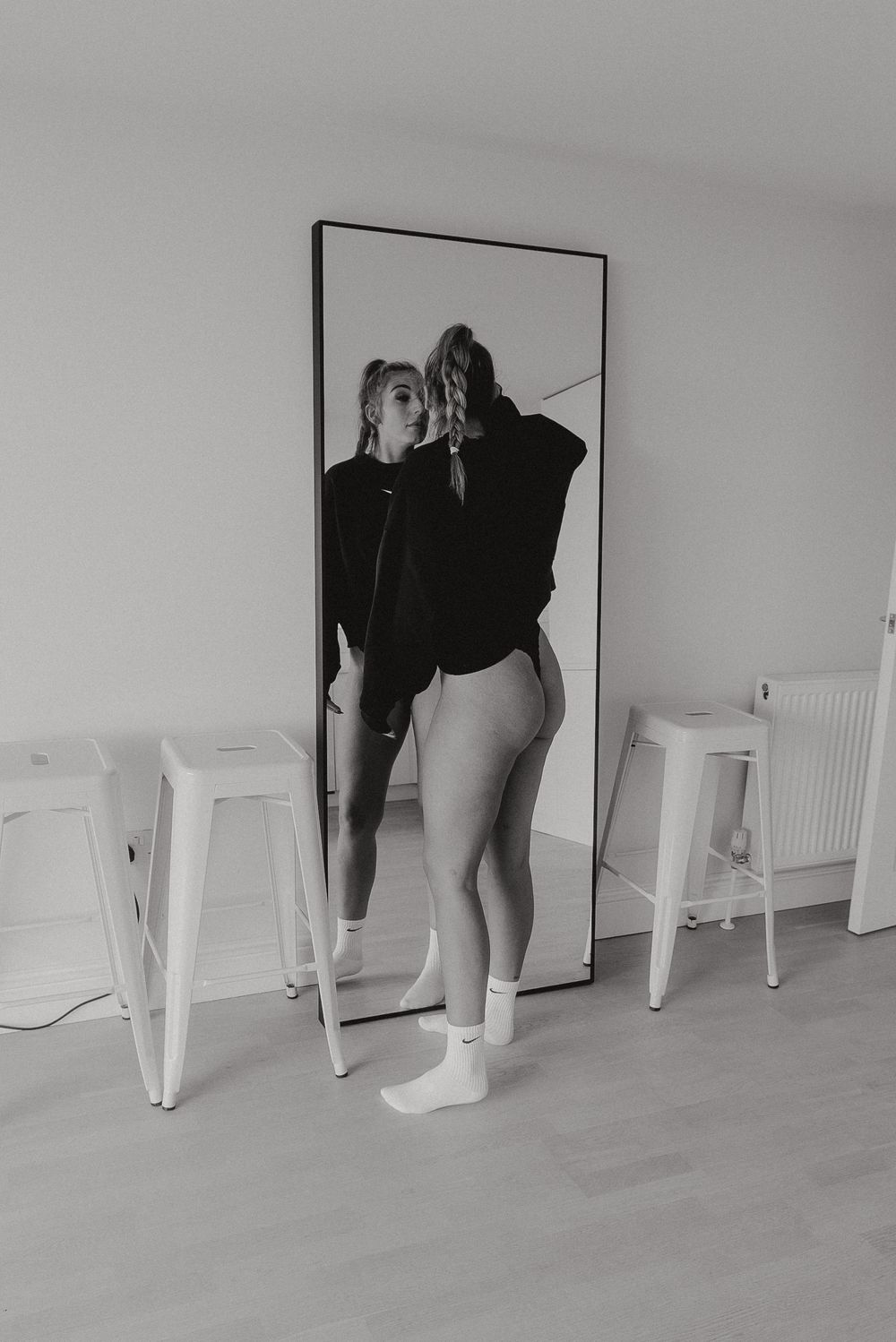 Minimalist mirror self-portrait in black and white with white chairs.
