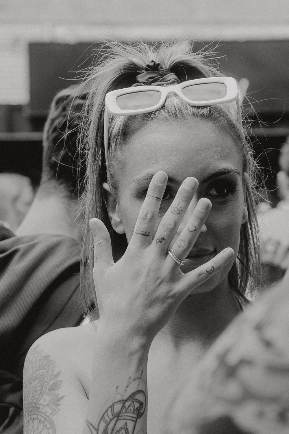 Playful portrait with white sunglasses and hand gesture.