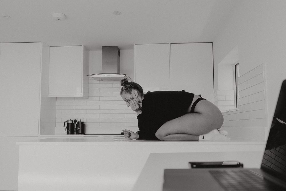 Artistic black and white photo of person on kitchen counter.