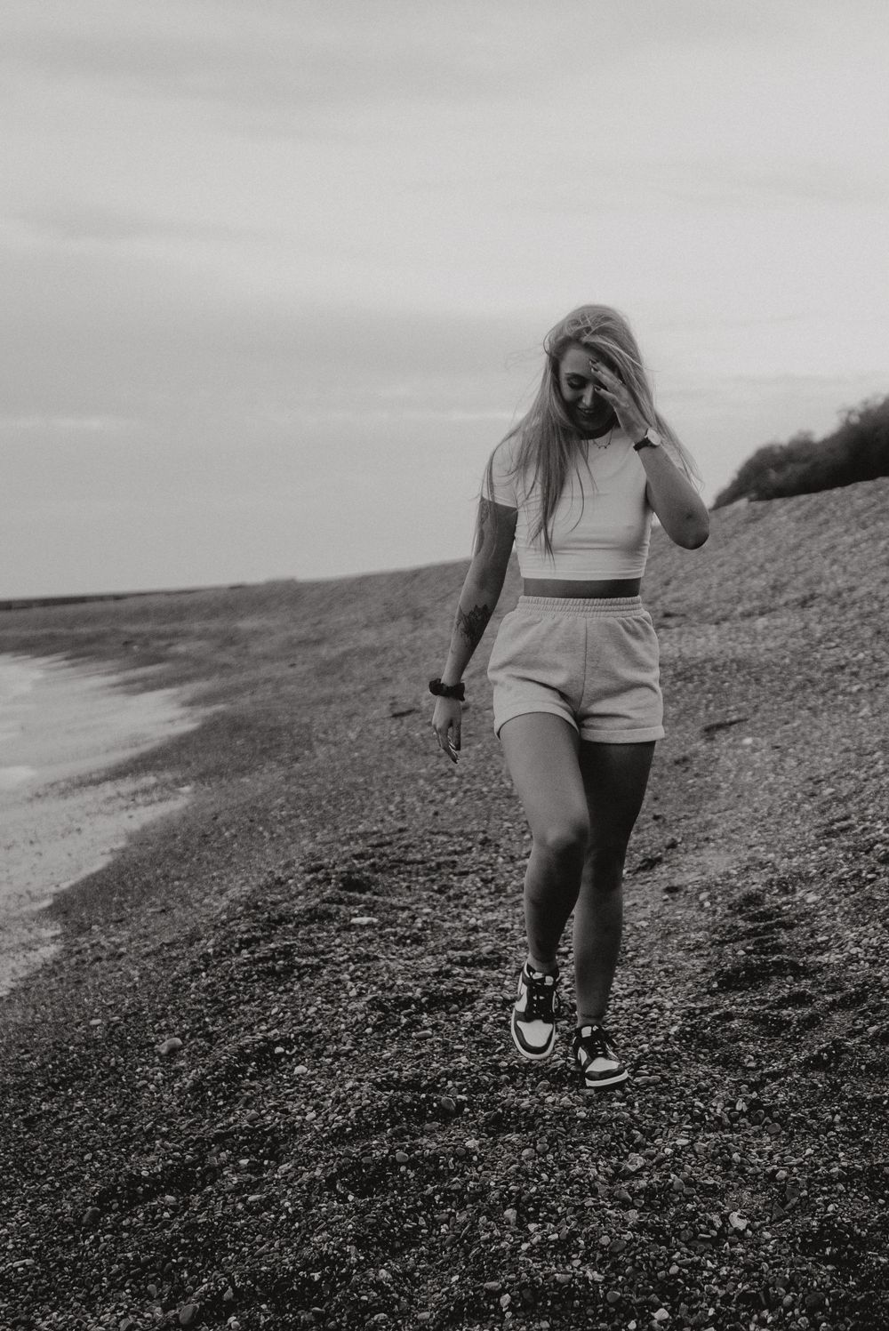 Person walking along coastal path wearing athletic wear and sneakers in black and white.