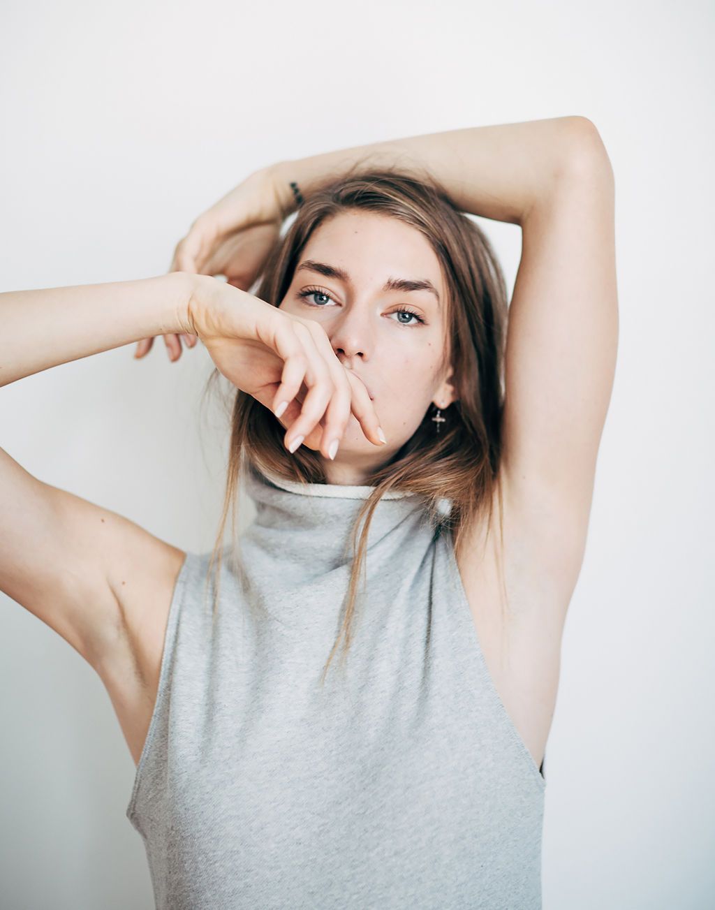 Artistic portrait of someone in a grey sleeveless top against white background.