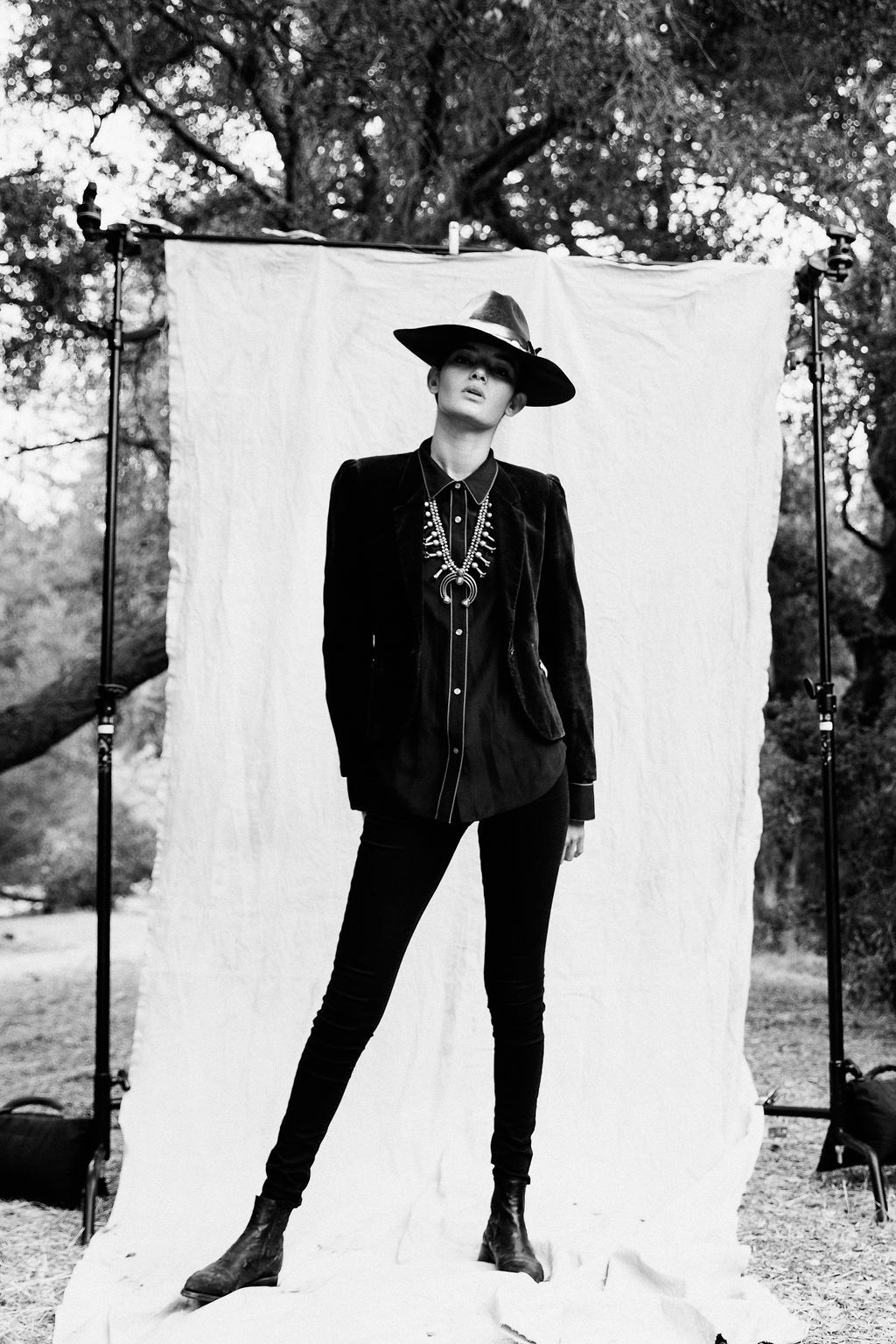 Full length black and white fashion photo against white backdrop featuring western-inspired styling.