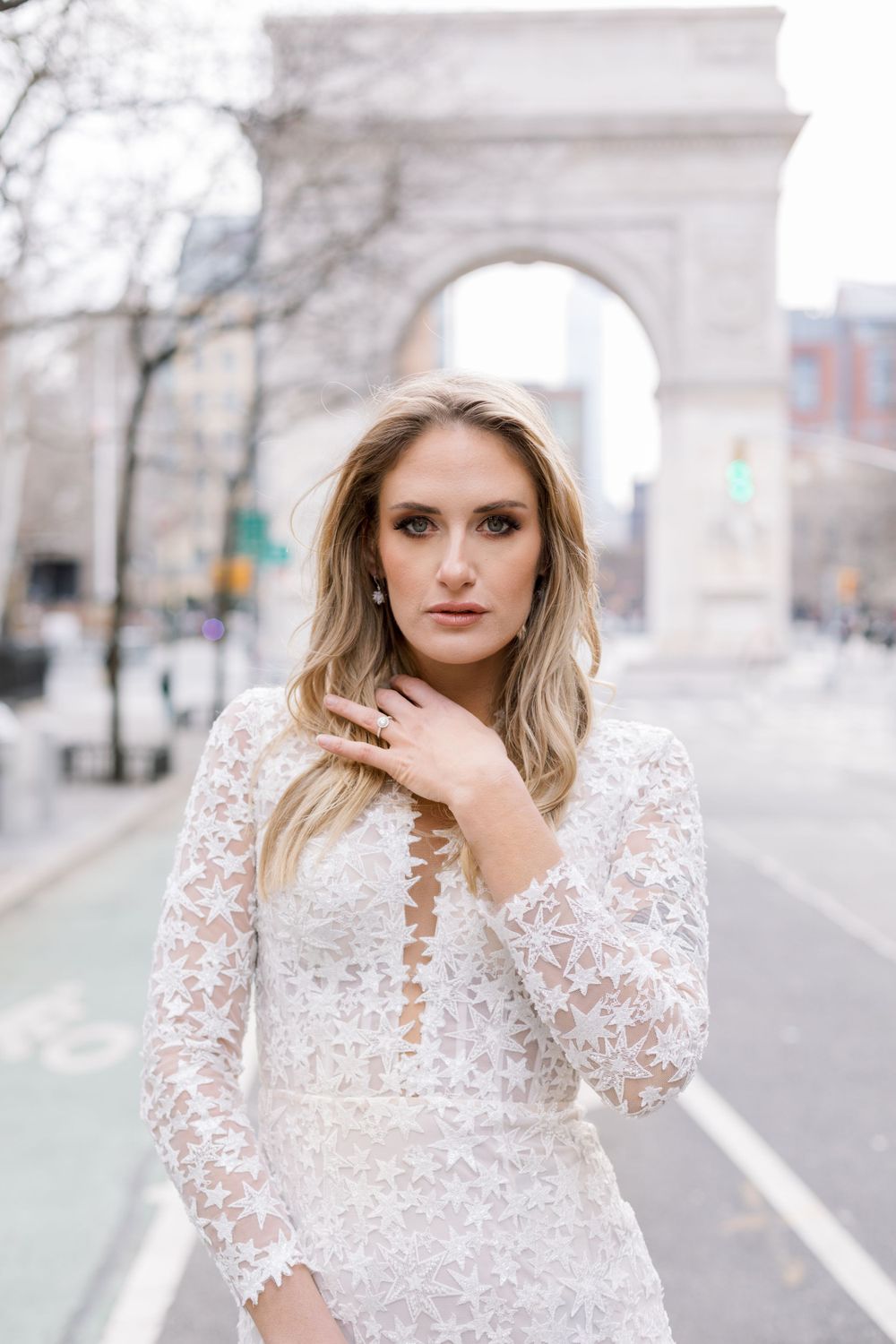 Elegant bridal portrait featuring delicate lace wedding gown near iconic arch monument.