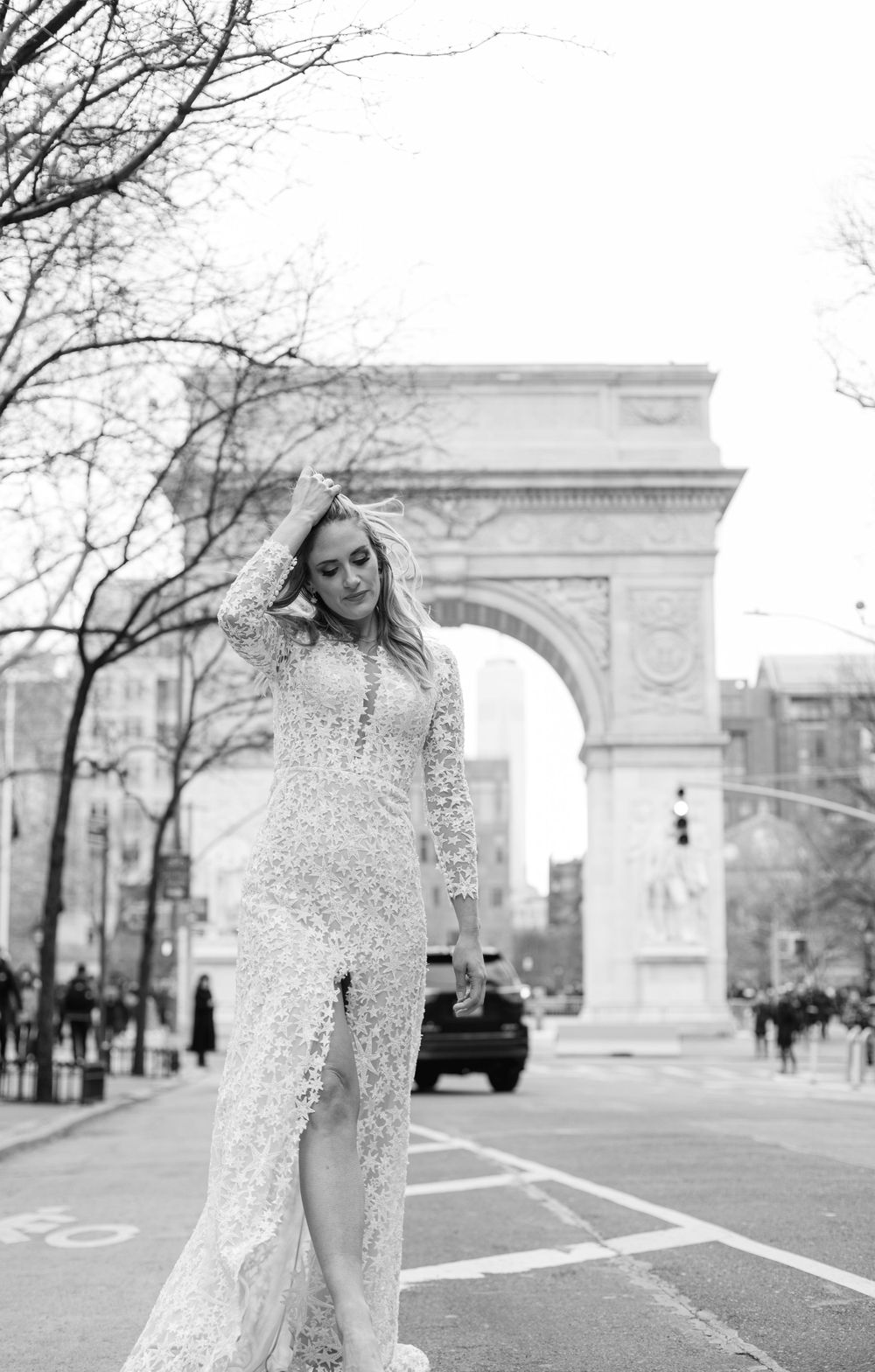Elegant lace wedding dress captured in black and white with Washington Square Arch in background.