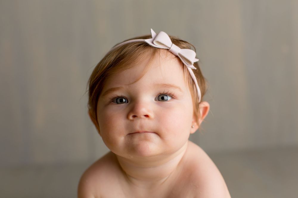 Studio portrait with soft lighting and a pink bow headband.