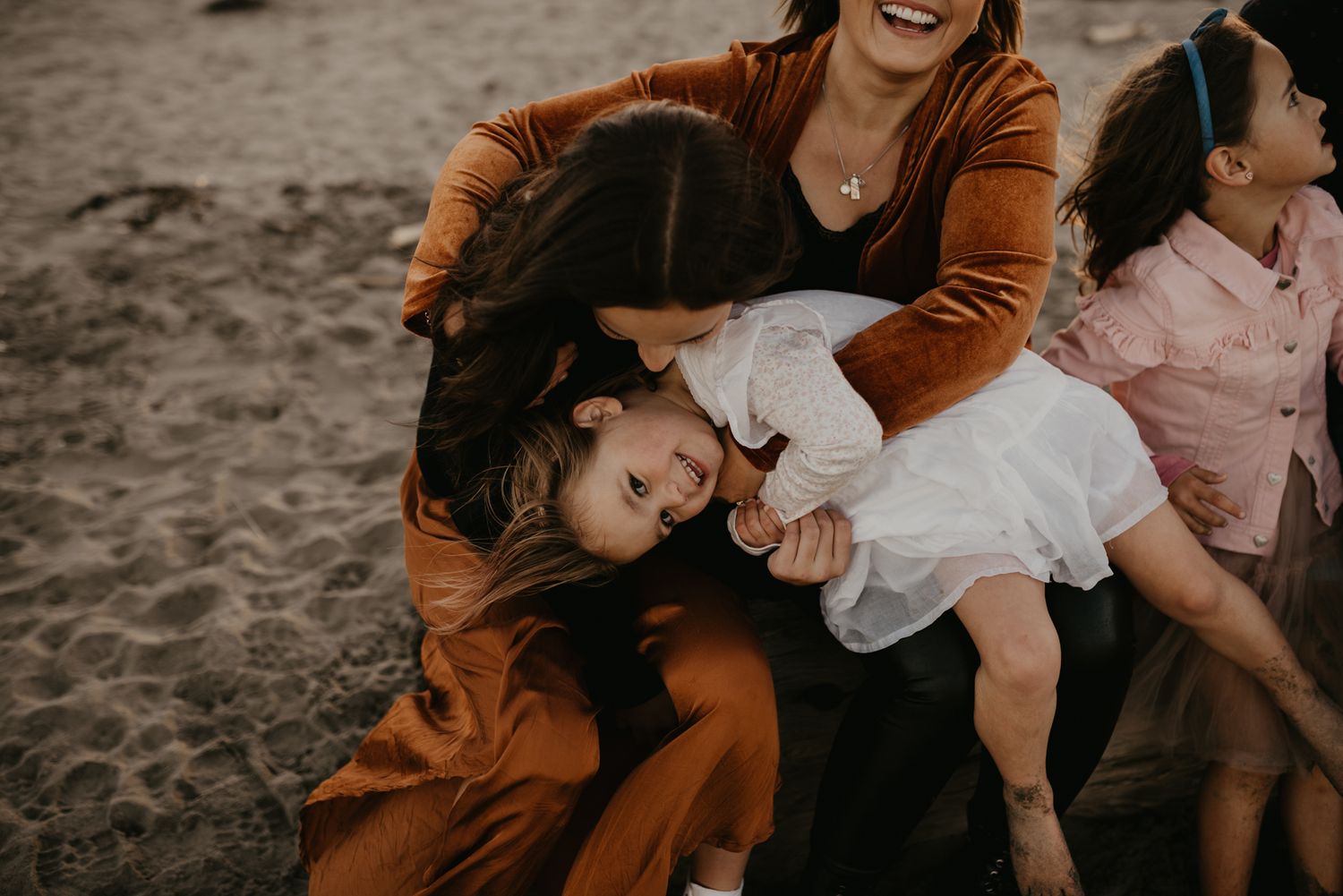Family sharing joyful moments together on beach in warm autumn tones.