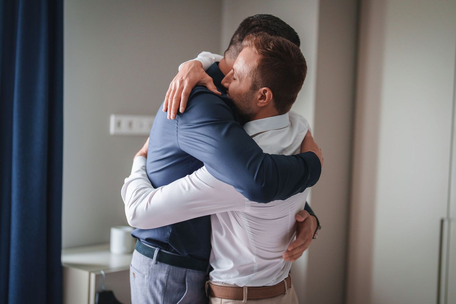 Two people share an emotional embrace while wearing formal attire.