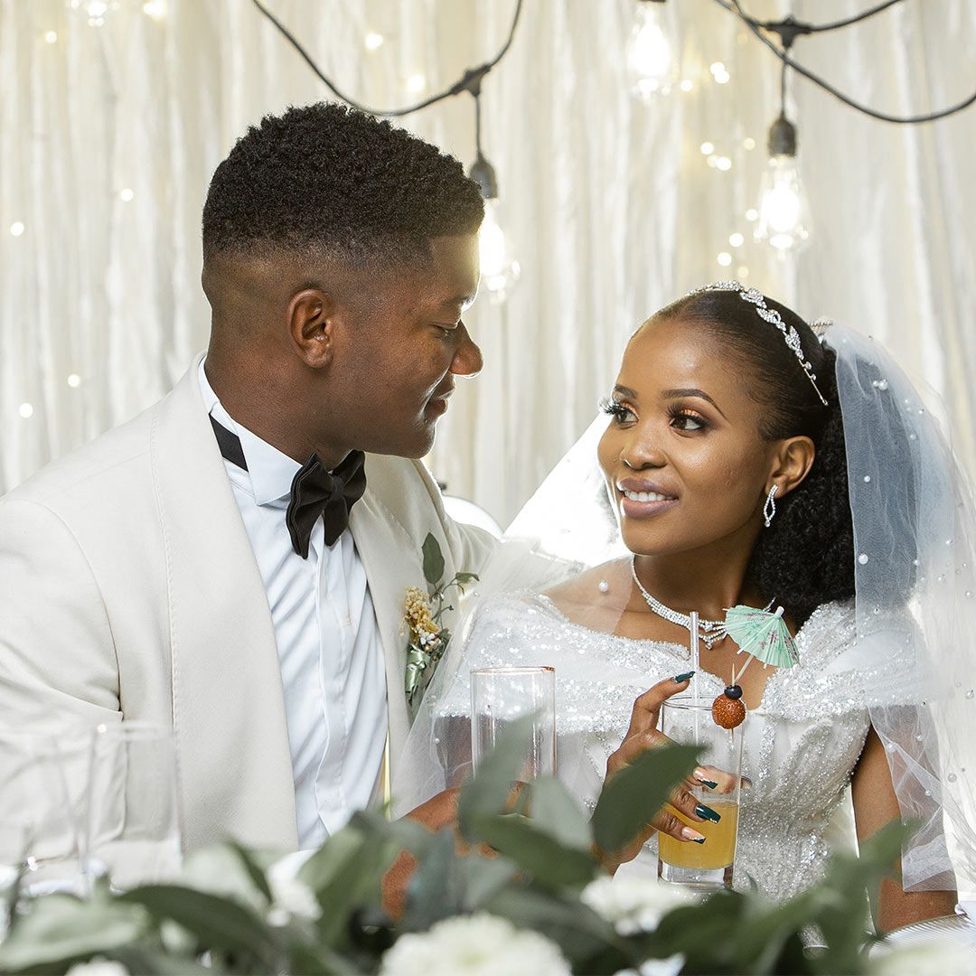 Newlyweds share intimate moment under twinkling lights.
