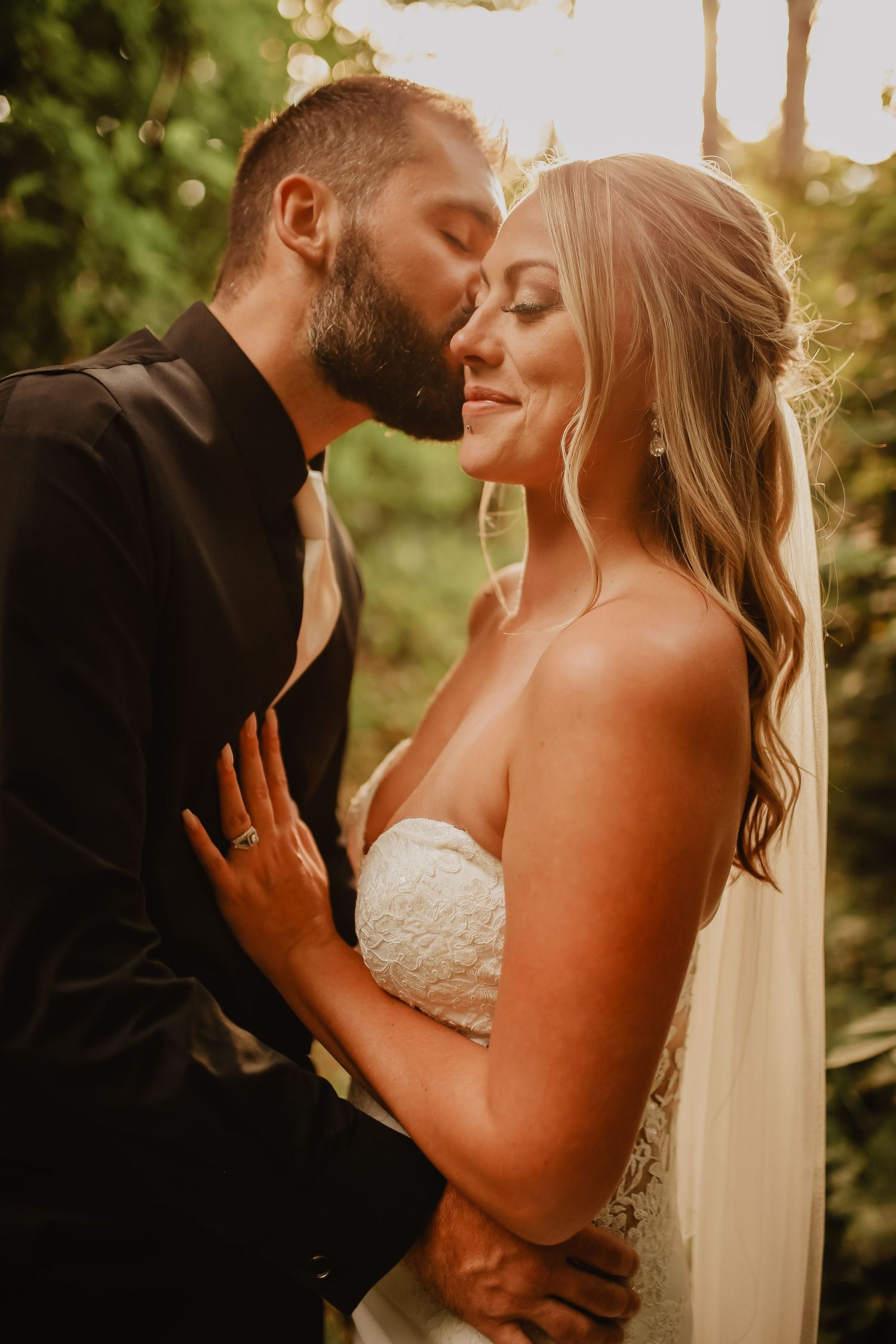 A romantic sunset wedding portrait showing tender embrace between newlyweds in golden light.