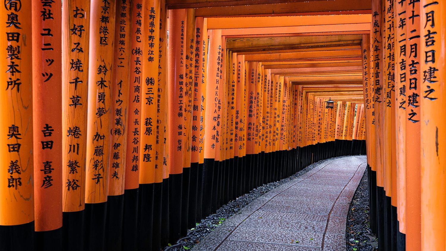 Long corridor of vibrant orange torii gates at a traditional Japanese shrine.