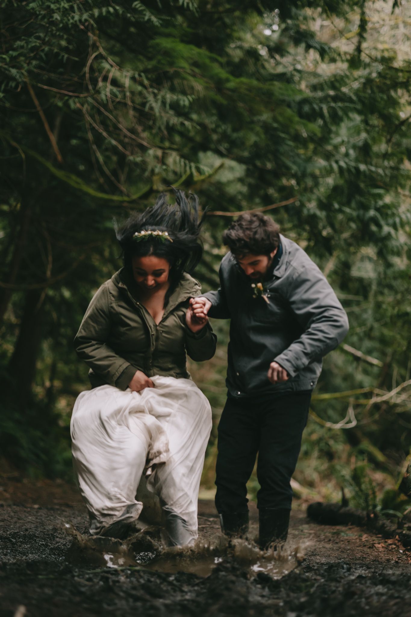 Couple in wedding attire jumping in a mud puddle making a splash