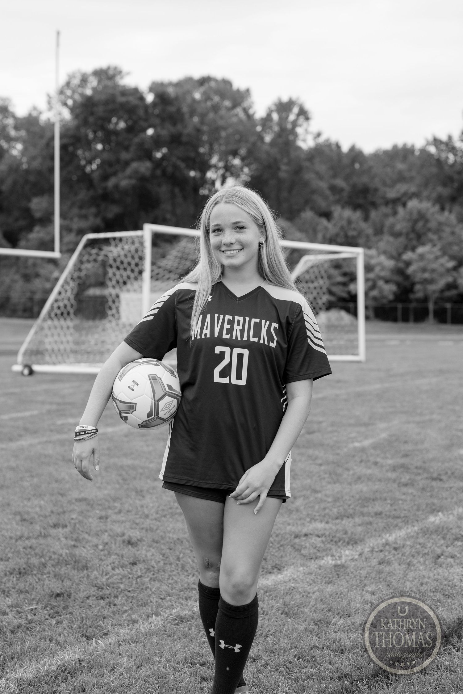 Black and white portrait of player in Mavericks jersey holding soccer ball.