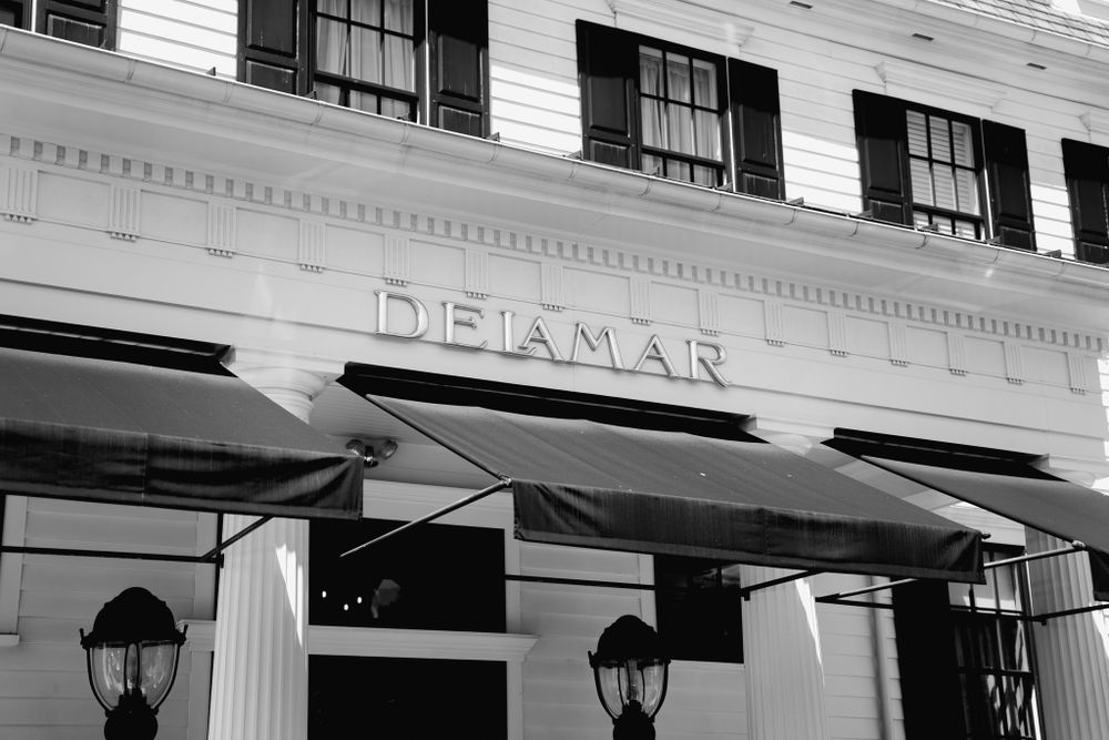 Black and white exterior view of the Delamar building with awnings and vintage light fixtures.