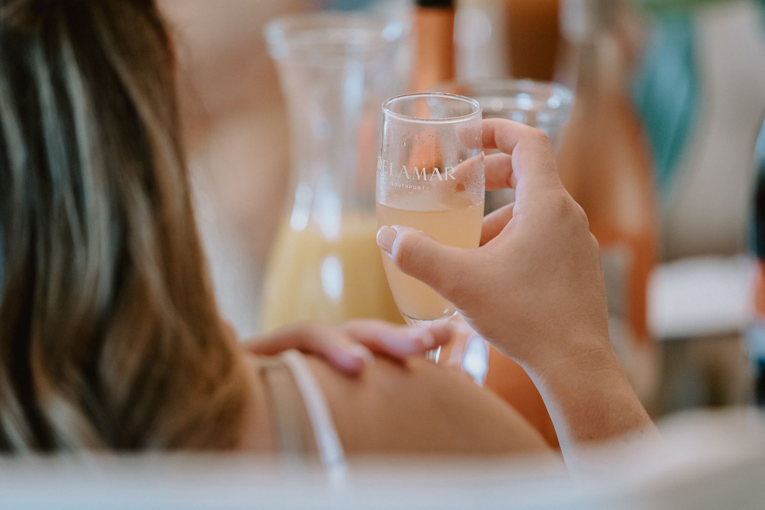 Hand holding a champagne glass with mimosas being served at a celebratory brunch.