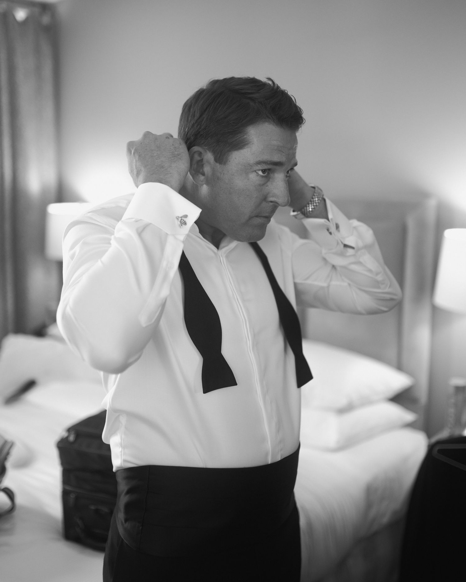 Black and white photo of formal wear preparation with bowtie adjustment.