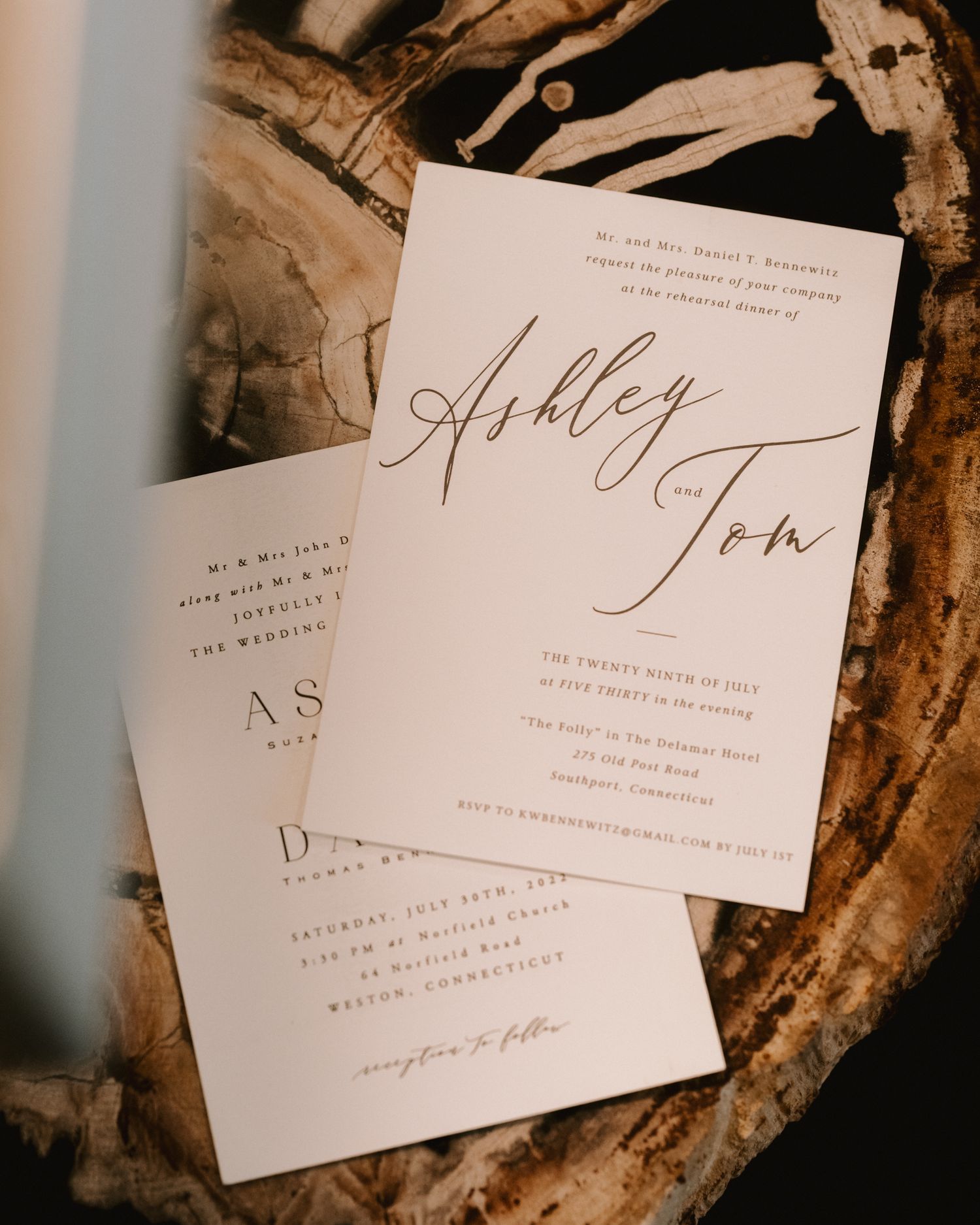 Elegant wedding invitation with calligraphy names Ashley and John on textured paper.