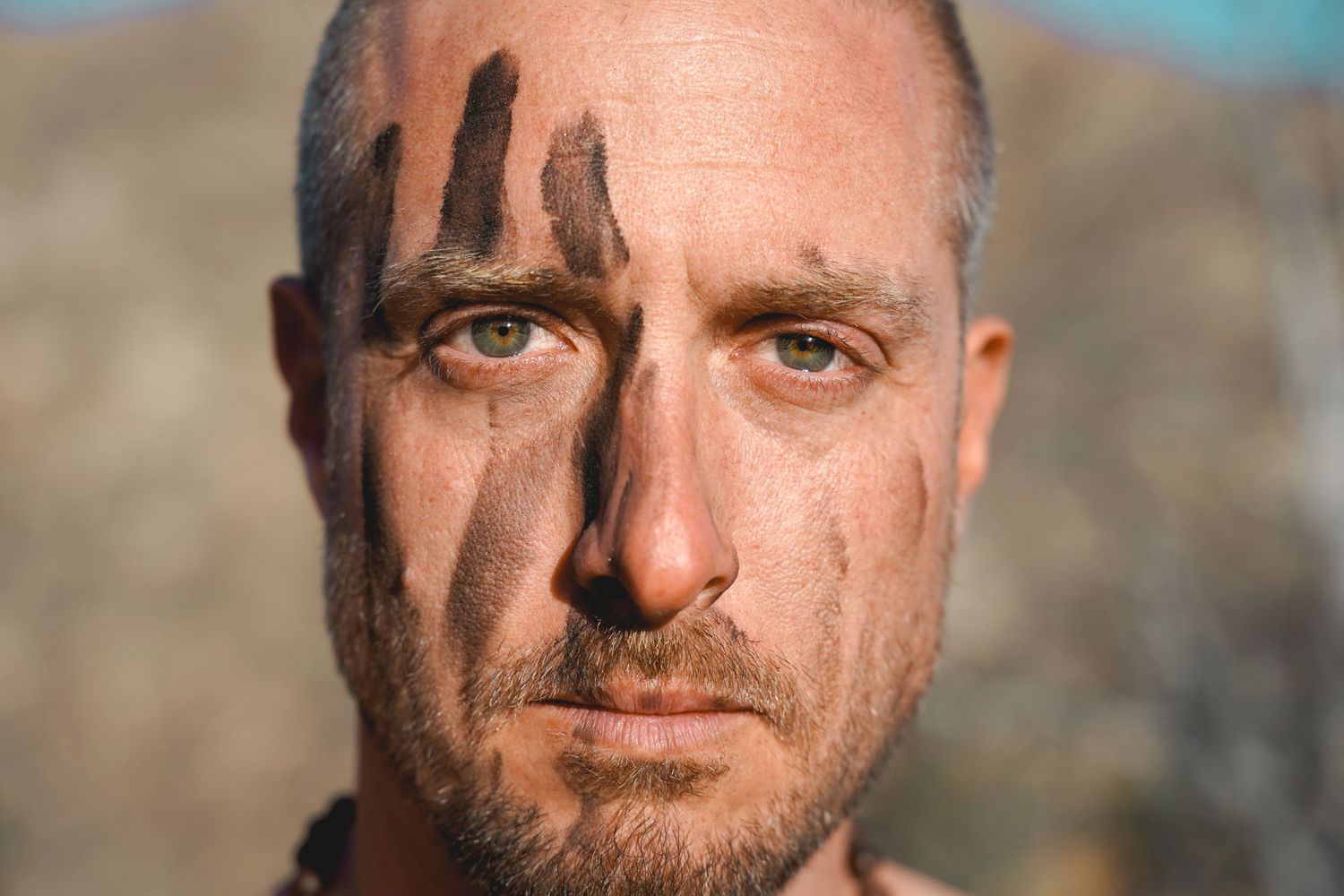 Close-up portrait with dramatic lighting highlighting intense facial features and expression.