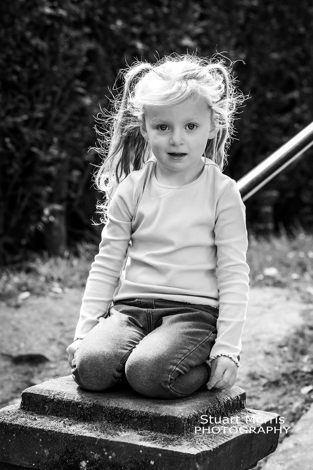 young girl kneeling on a stone pillar. relaxed natural portrait session. Stuart Morris Photography.