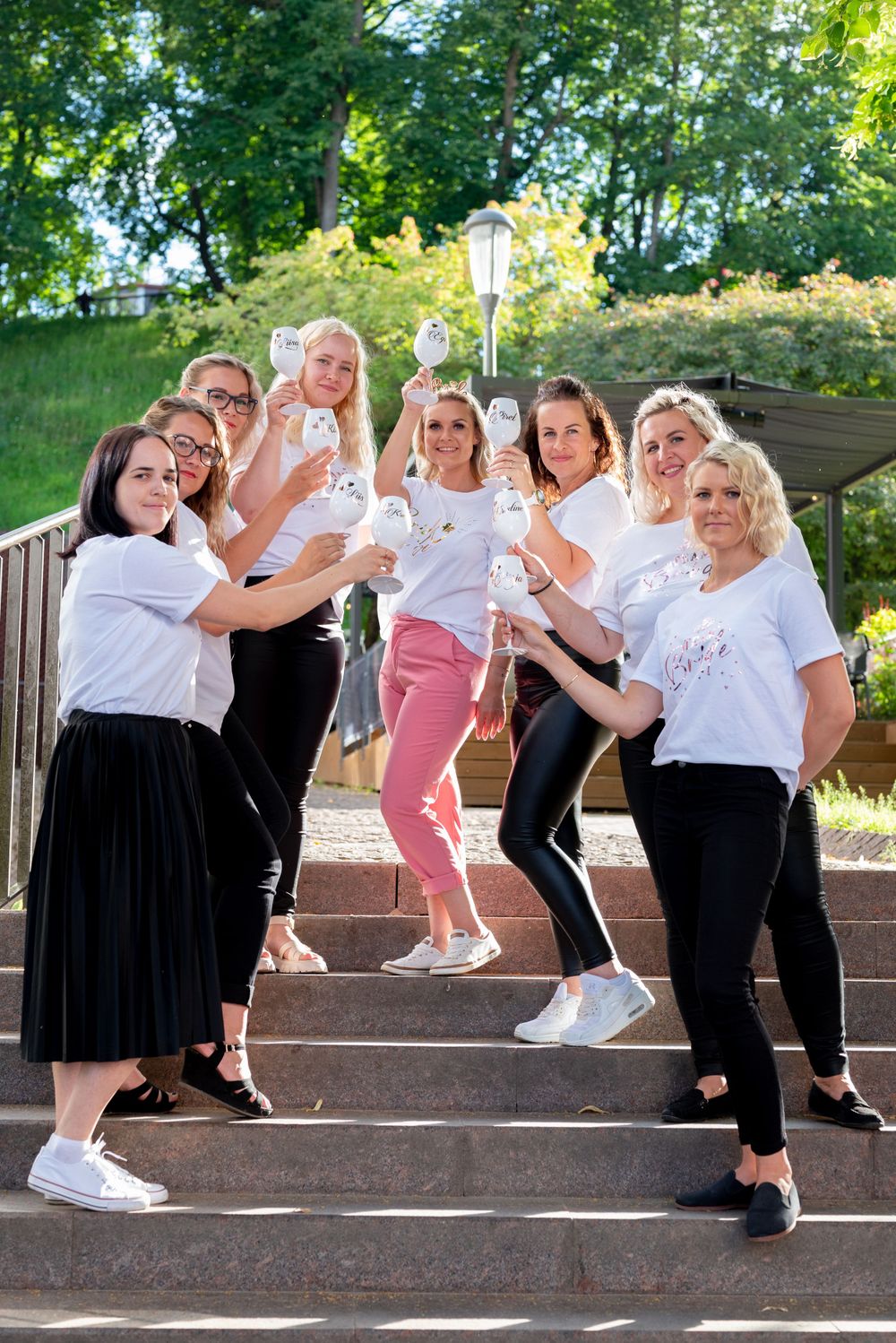 Friends in coordinated white shirts strike a fun pose on outdoor steps with balloons.