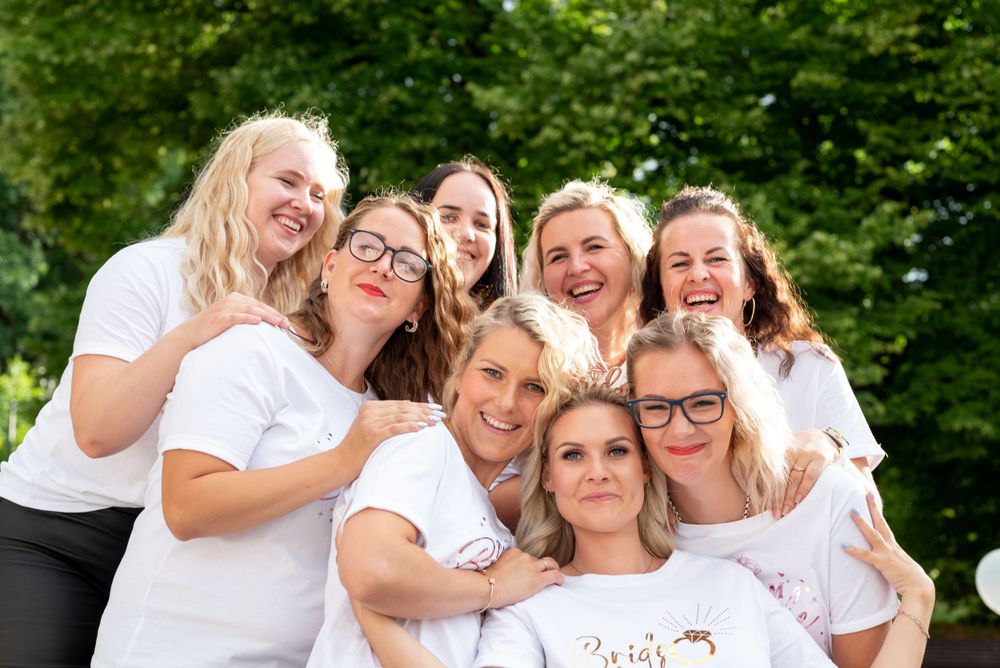 Friends wearing coordinated white shirts huddle together for a fun group photo outdoors.