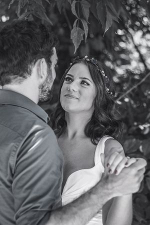 Black and white portrait of romantic couple sharing intimate moment under tree branches.