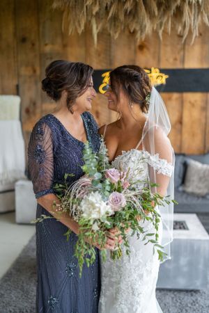 Emotional mother-daughter moment at wedding with elegant floral bouquet.
