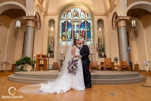 Wedding ceremony in a church with stained glass windows and arched architecture.
