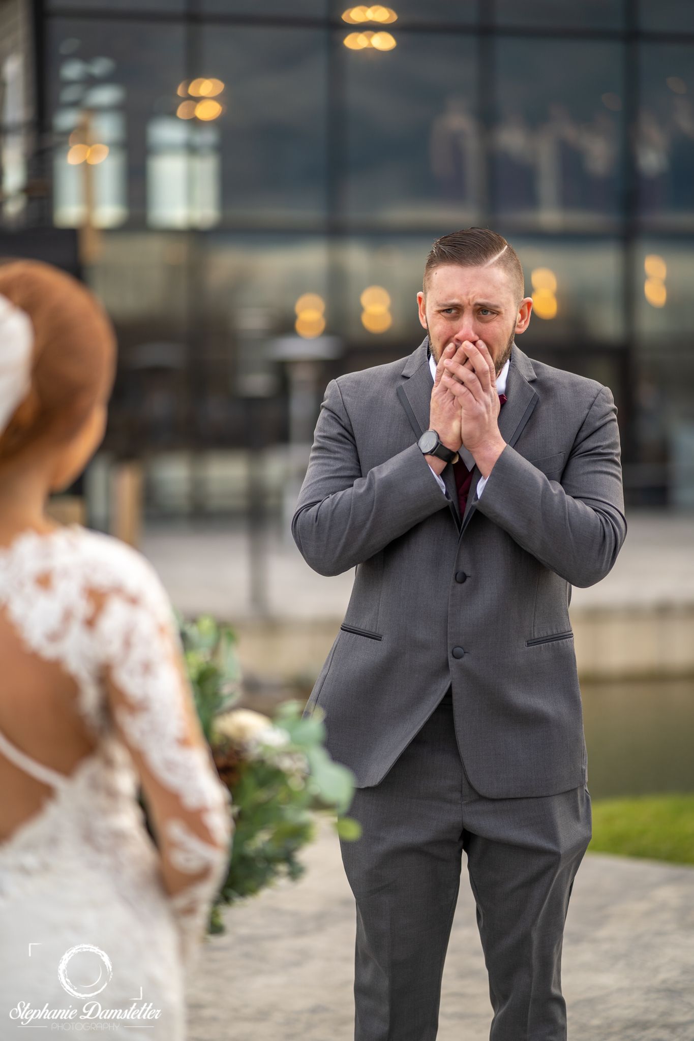 An emotional first look reaction during a wedding ceremony with the groom covering his mouth in surprise.