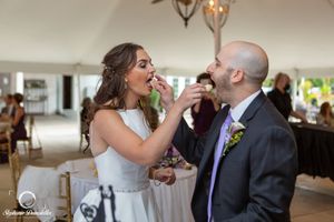 Wedding couple sharing cake during reception celebration indoors.
