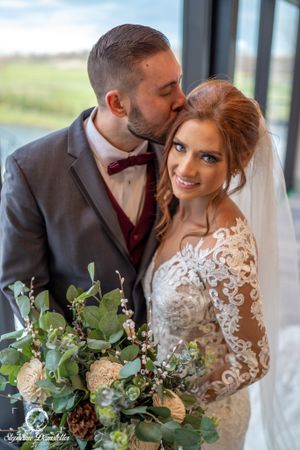 A romantic wedding portrait with a peach and eucalyptus bouquet in an elegant indoor setting.