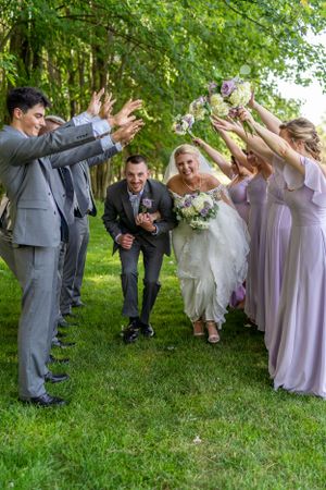 Fun wedding party photo with bridesmaids and groomsmen creating a tunnel for the newlyweds.