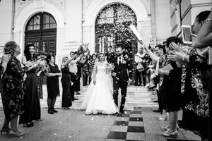 Wedding exit celebration with guests throwing confetti outside grand archway.