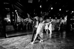 Black and white photo of wedding guests dancing energetically on reception dance floor.