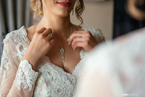 Close-up detail of delicate lace wedding dress with necklace.